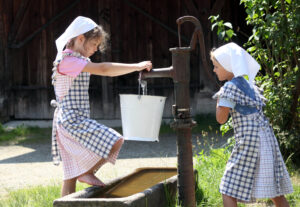 Zwei Kinder die am Brunnen Wasser holen