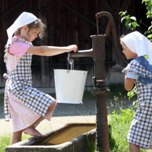 Zwei Kinder die am Brunnen Wasser holen